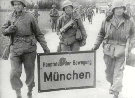 Foto von Soldaten mit einem Schild mit der Aufschrift "Hauptstadt der Bewegung: München"