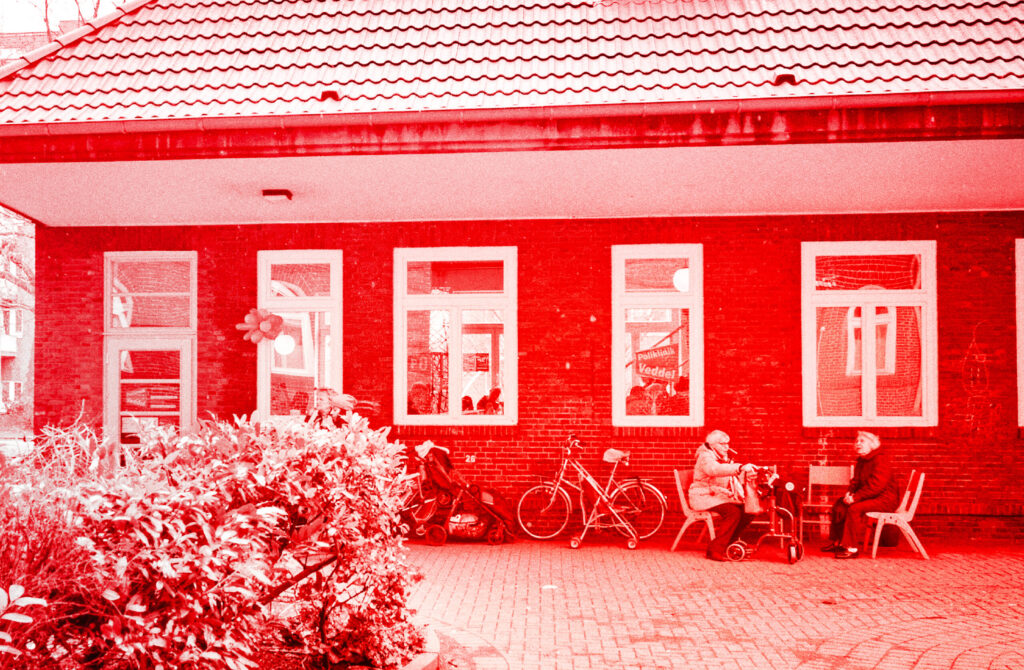 Foto der Poliklinik in Veddel mit zwei älteren Personen und Fahrrad davor